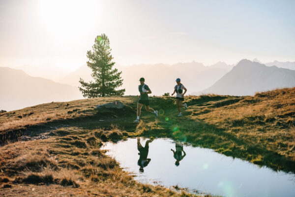 Deux traileurs courant le long d'un lac en montagbe